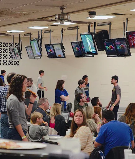 Adults and children eating, socializing, and bowling together at Southland Bowling Lanes